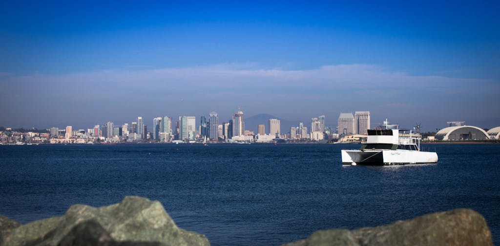 Bright view of San Diego's skyline with a boat on the bay, showcasing urban and maritime beauty.